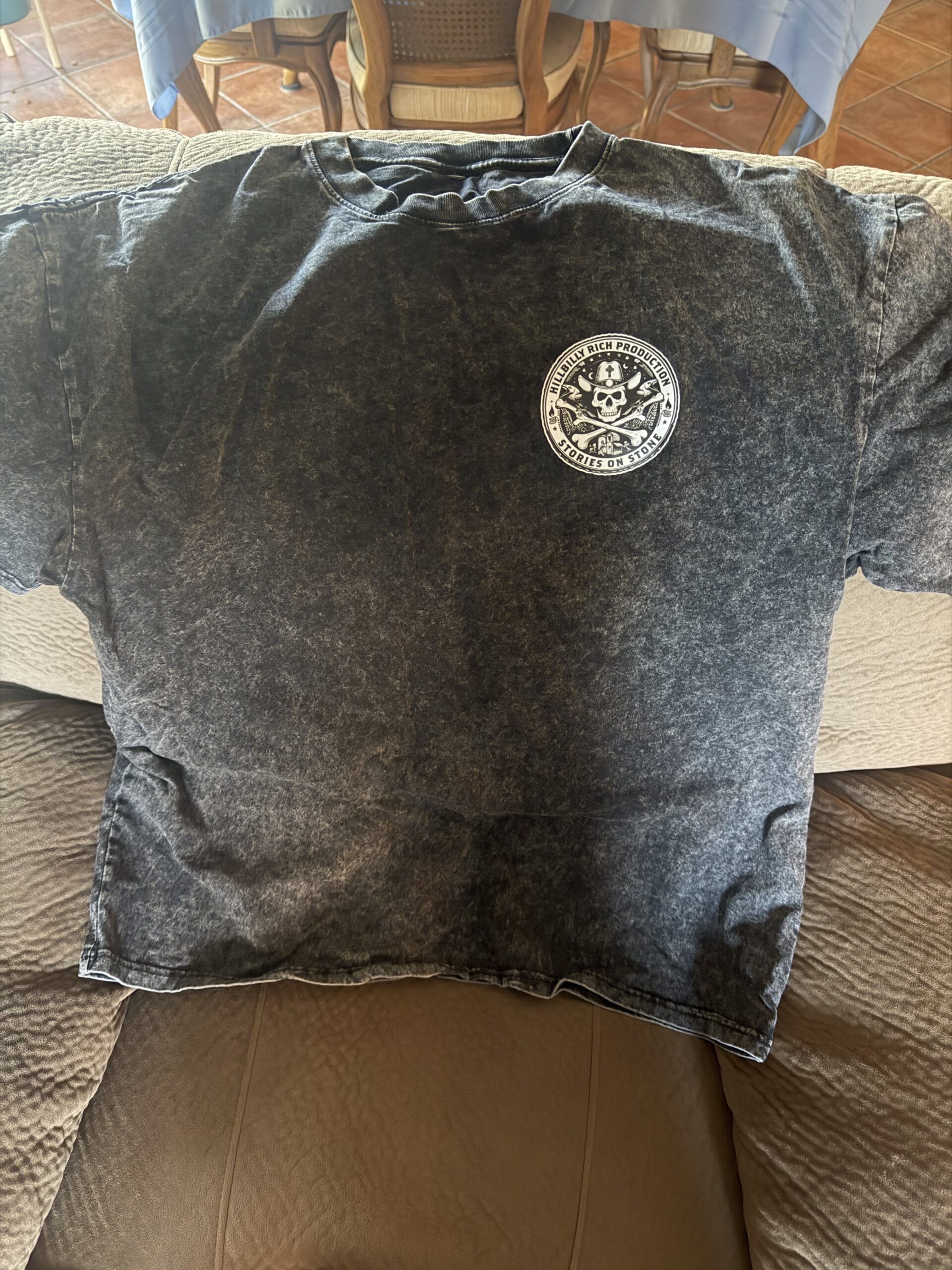 Black vintage-style t-shirt featuring a round graphic with a skull and crossbones design